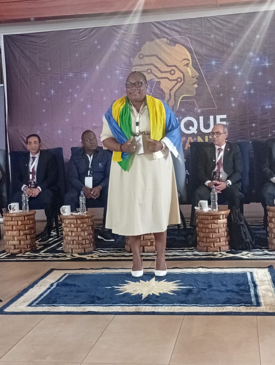 Lauréate face au jury, drapée du drapeau gabonais